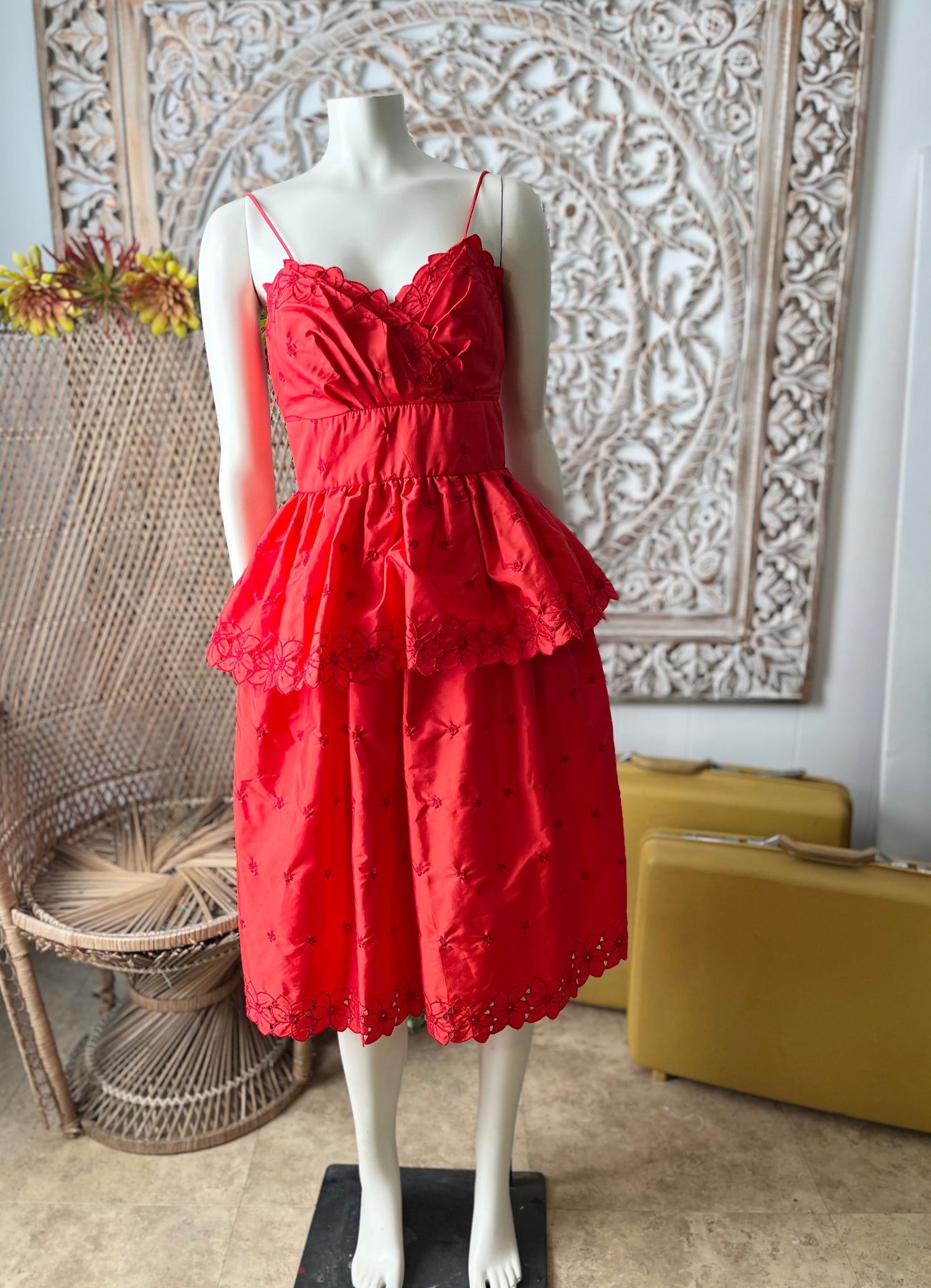 Red lace dress on a mannequin against a decorative wall.