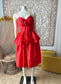 Red lace dress on a mannequin against a decorative wall.