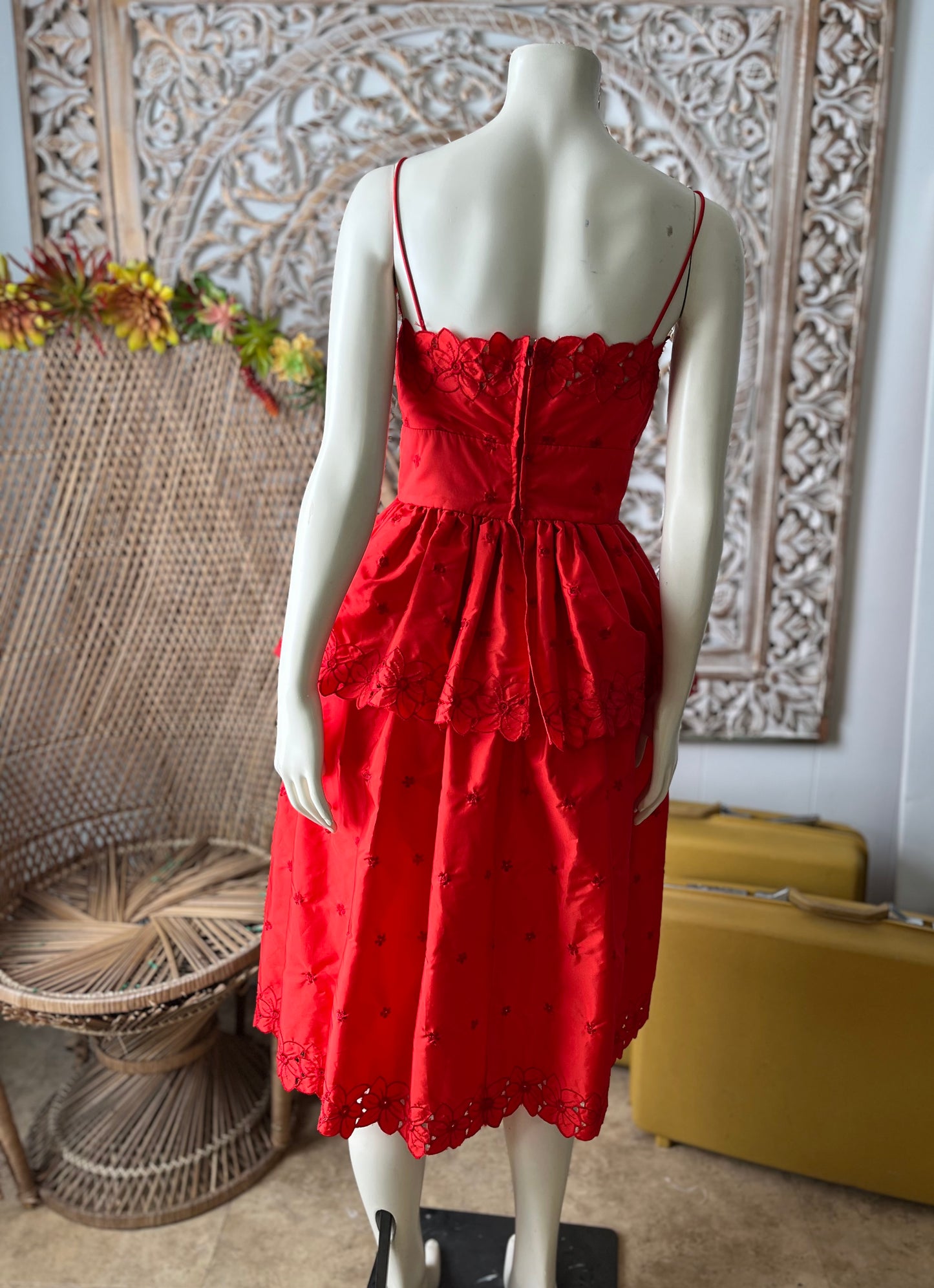 Red dress on a mannequin against a decorative wall.