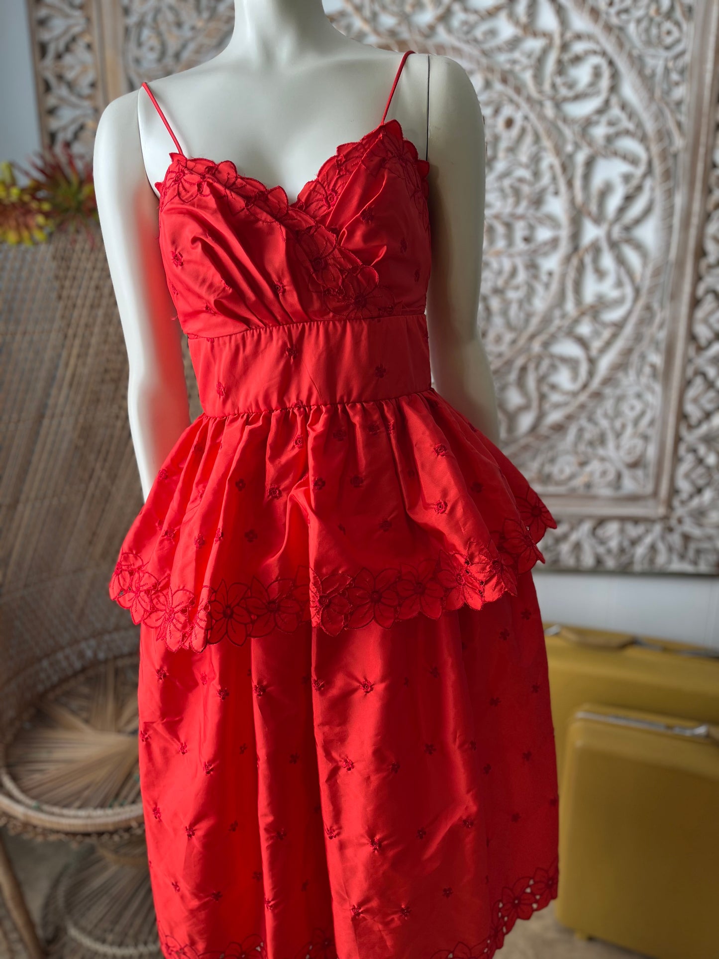 Red dress on a mannequin against a decorative wall.