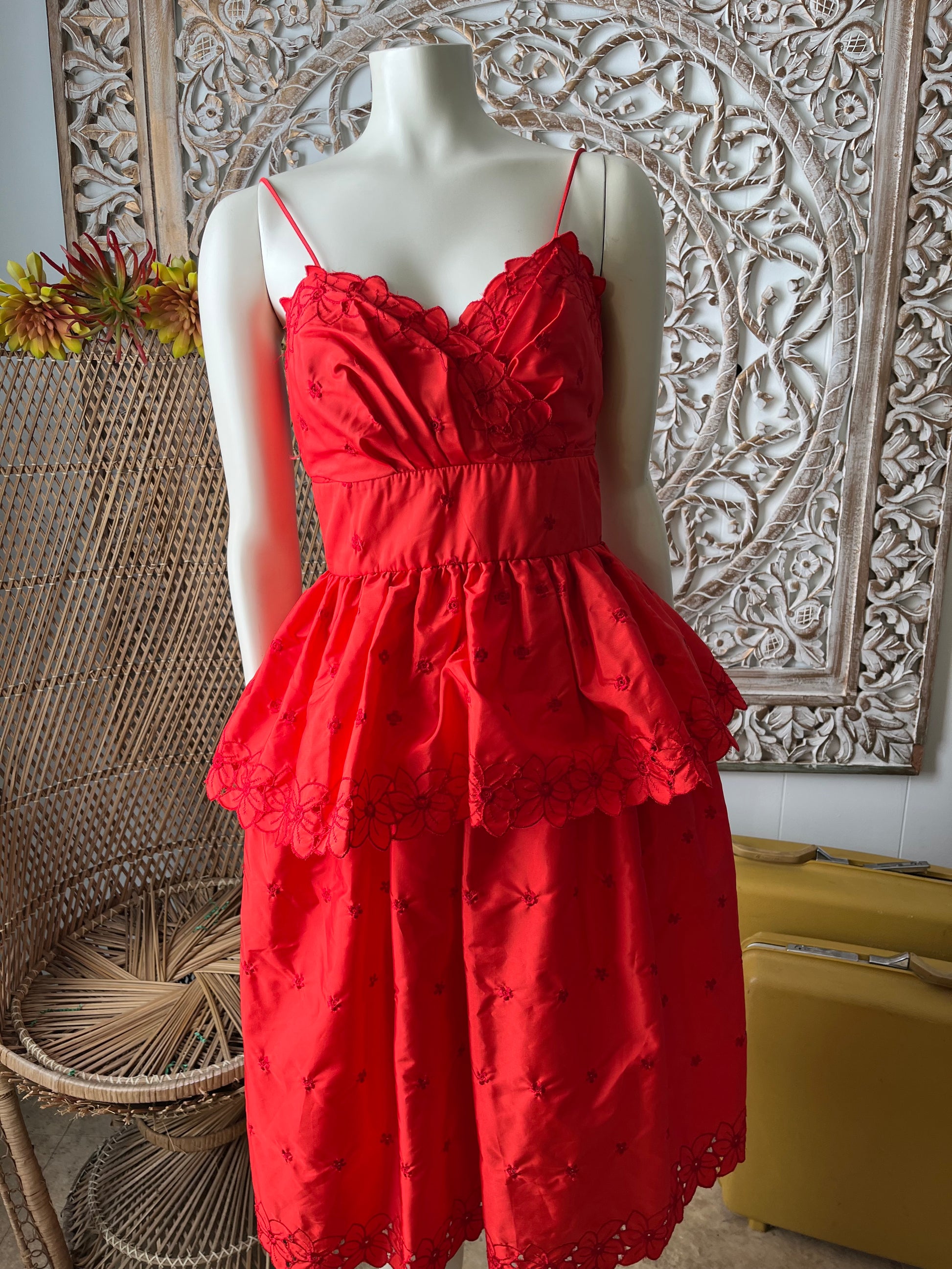 Red dress on a mannequin against an ornate wall.