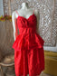 Red dress on a mannequin against an ornate wall.